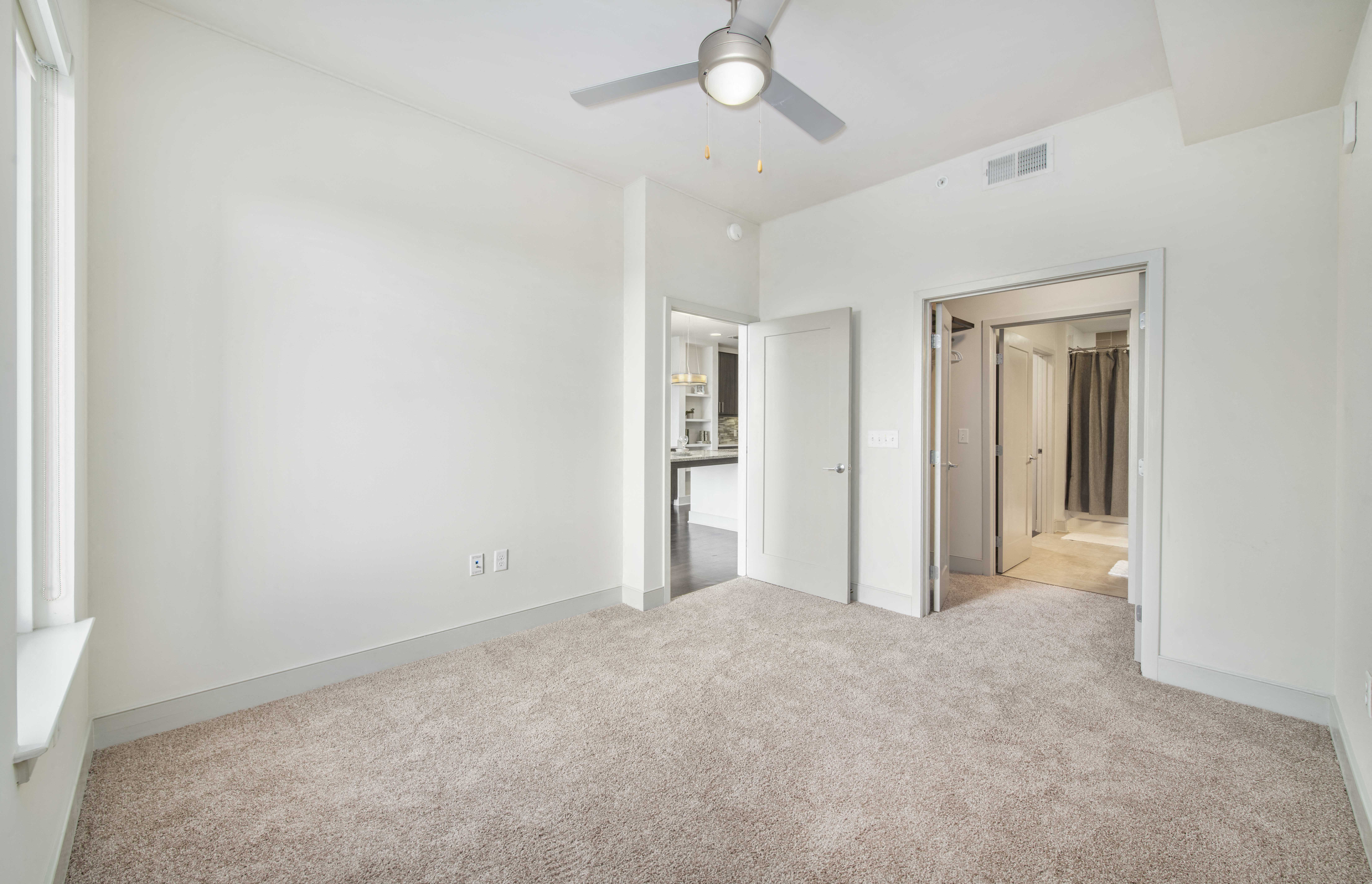 a living room with carpet and a ceiling fan